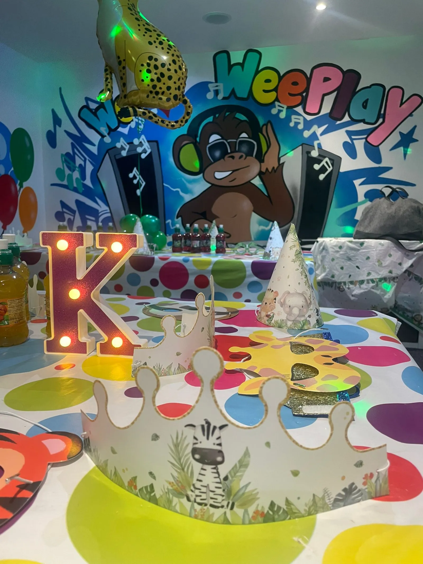 A birthday party table set with safari party hats under the WeePlay mural